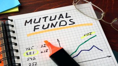 A highlighter sits on top of a notebook with the words "mutual funds" written on it.